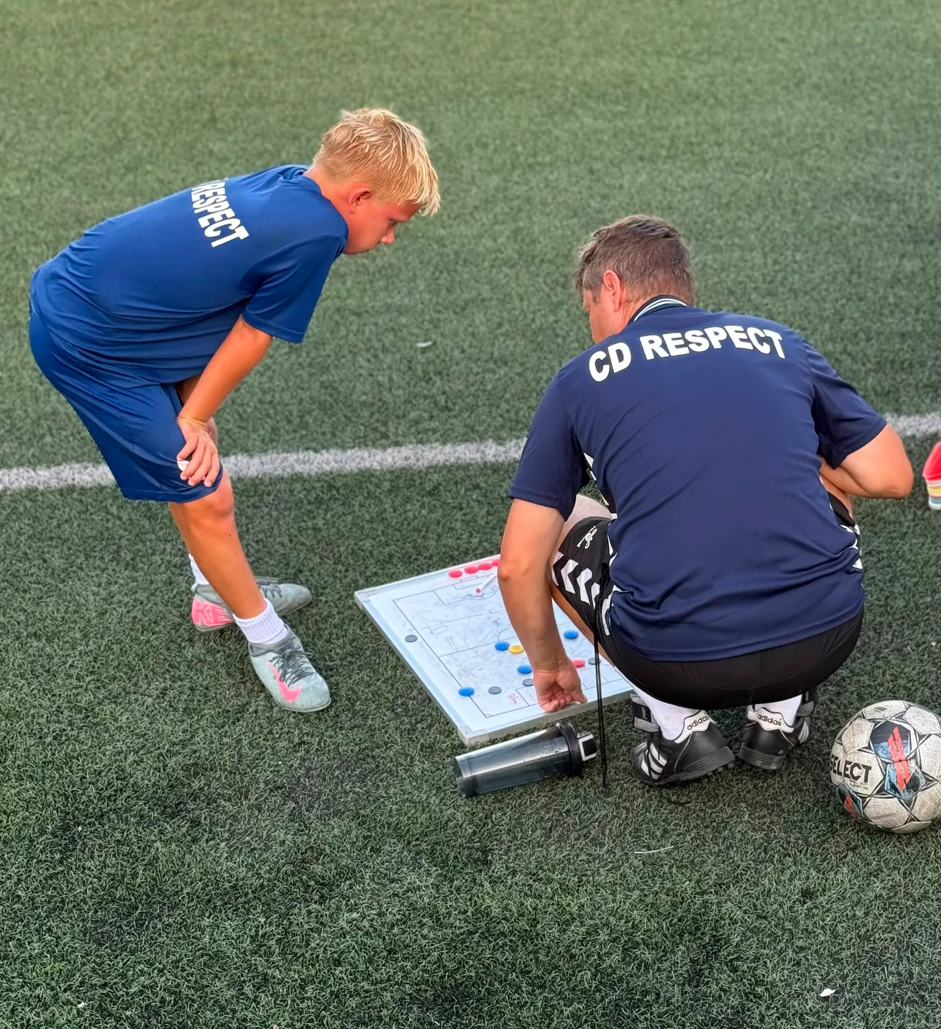 Entrenador de Respect explicando tácticas en una pizarra a un joven jugador